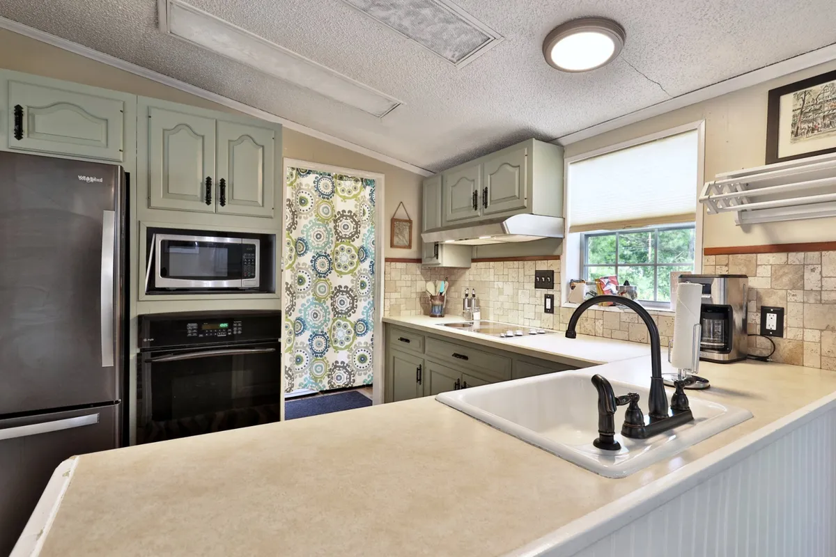 A modern, functional kitchen highlighted by a spacious island, colorful curtains, sleek appliances, and a decorative backsplash. The setup is ideal for meal prep, baking, and socializing, reflecting the kitchen's role as a social hub.