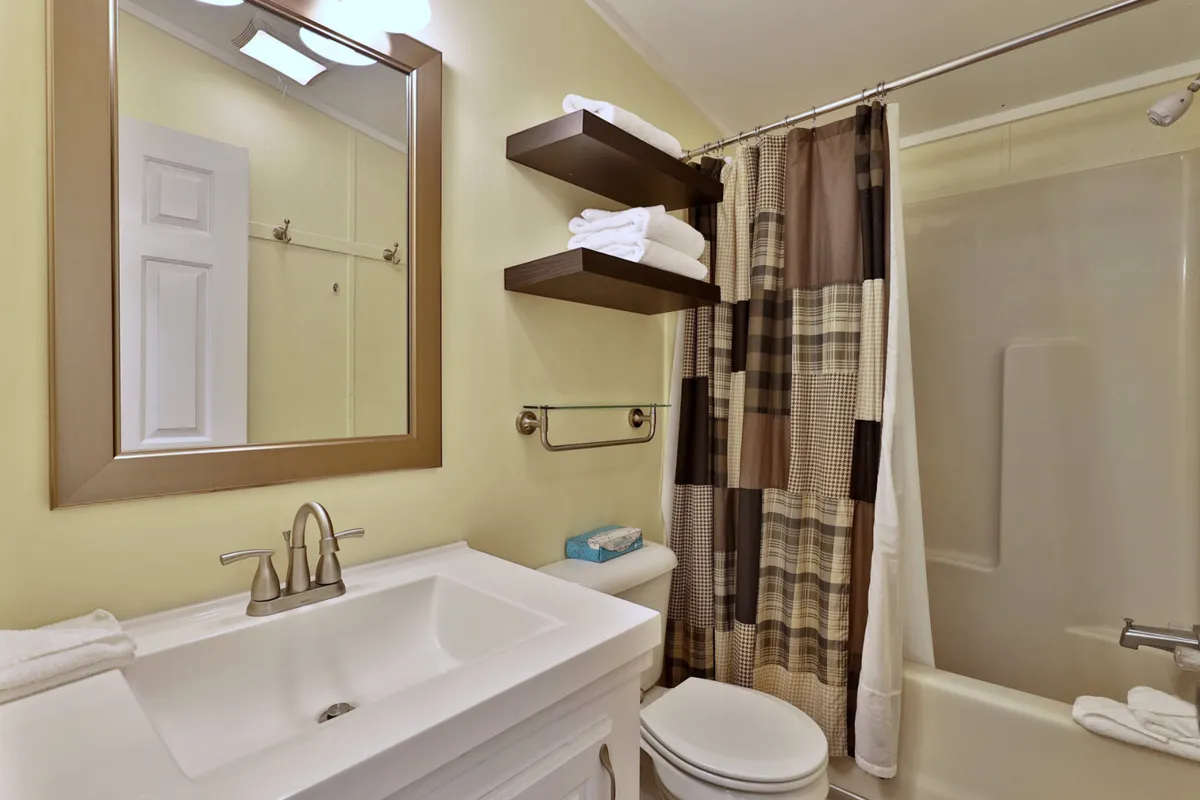 A fresh and organized bathroom with a sink, mirror, and shower curtain. The space is clean, practical, and ready for morning or evening routines.