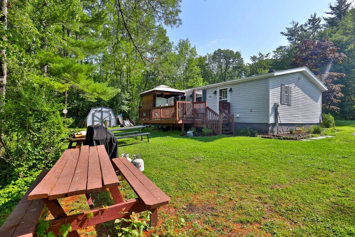 This image showcases a welcoming outdoor deck with a picnic table surrounded by lush greenery and a garden area. The scene is set for outdoor dining and family gatherings, providing ample space for activities like picnics, games, and enjoying nature.