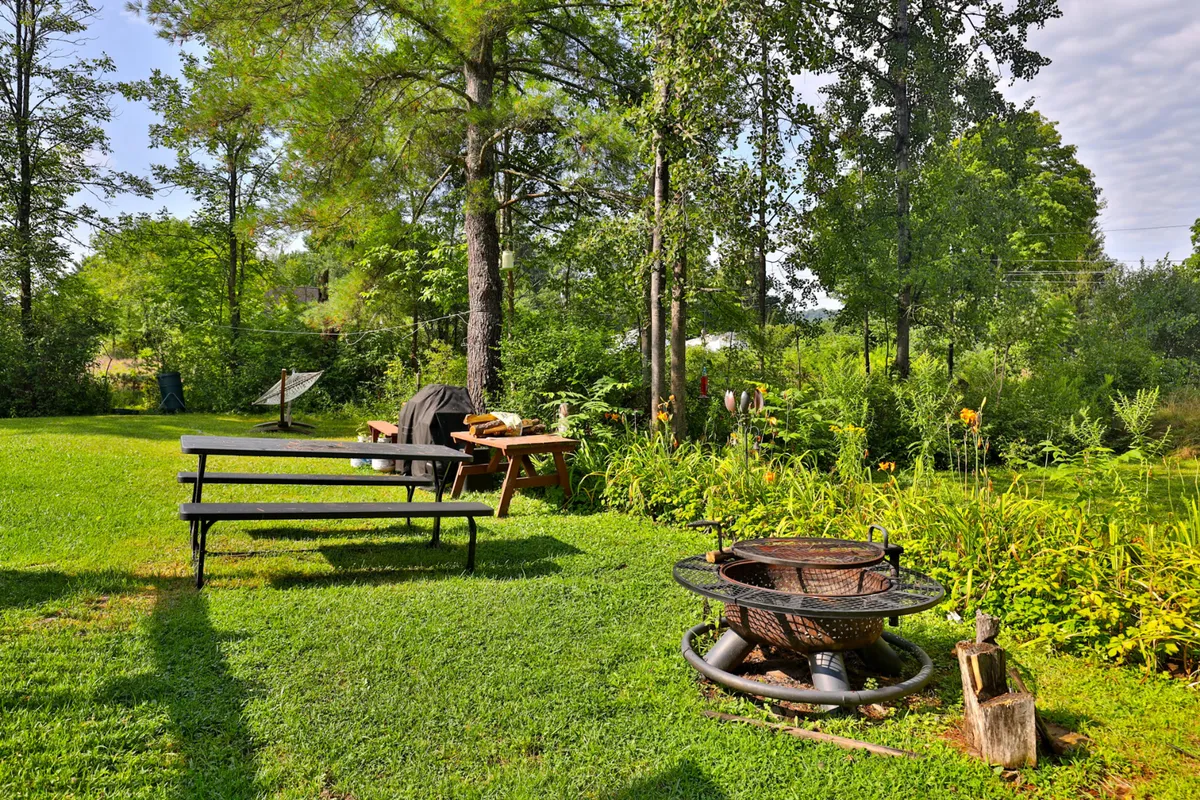 A welcoming fire pit area surrounded by benches and lush greenery, creating a cozy spot for evening gatherings, marshmallow roasting, or warming up after a winter day outdoors.